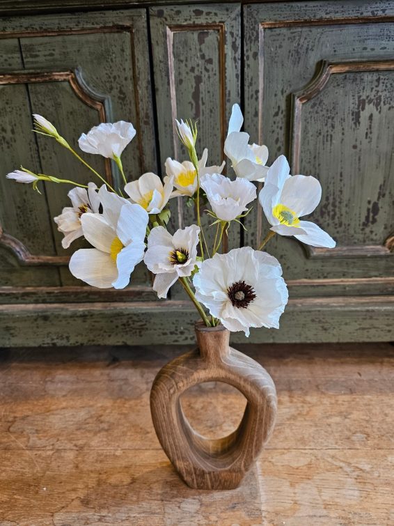 Witte papieren bloemen in een houten vaas.
