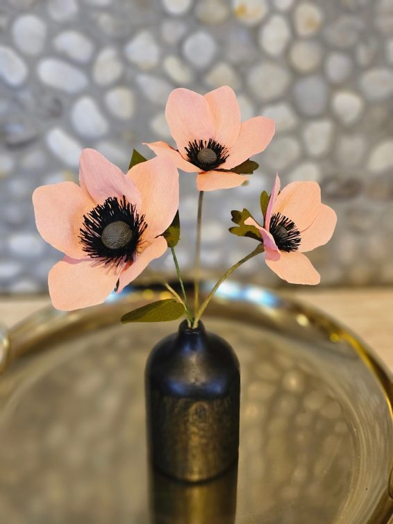 Zalmroze papieren anemonen in een zwart vaasje.